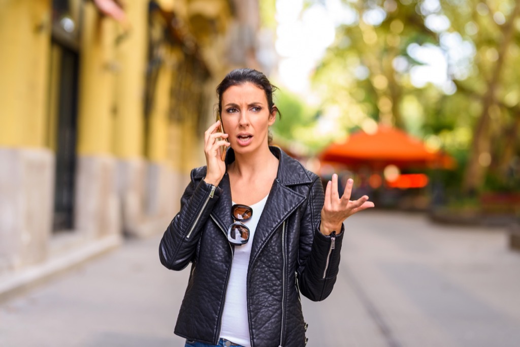 woman on street on heated phone call, things not to say to customer service rep