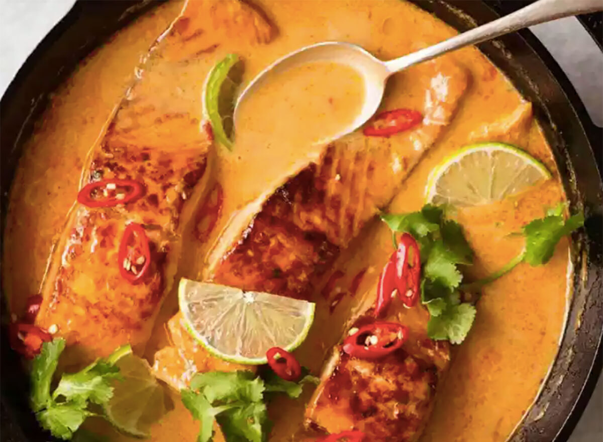 poached salmon in cast iron pan with chilies cilantro and lime wedge