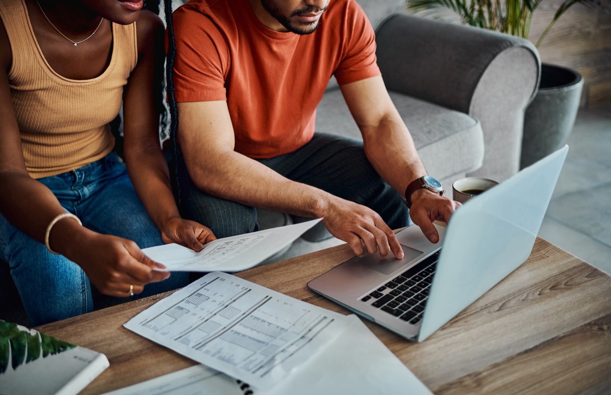 Man and woman sitting on couch doing taxes with laptop