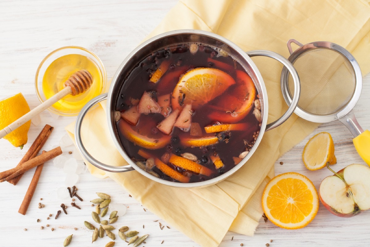 silver pan with fruit and cinnamon in it next to a clear bowl of honey with a dipper