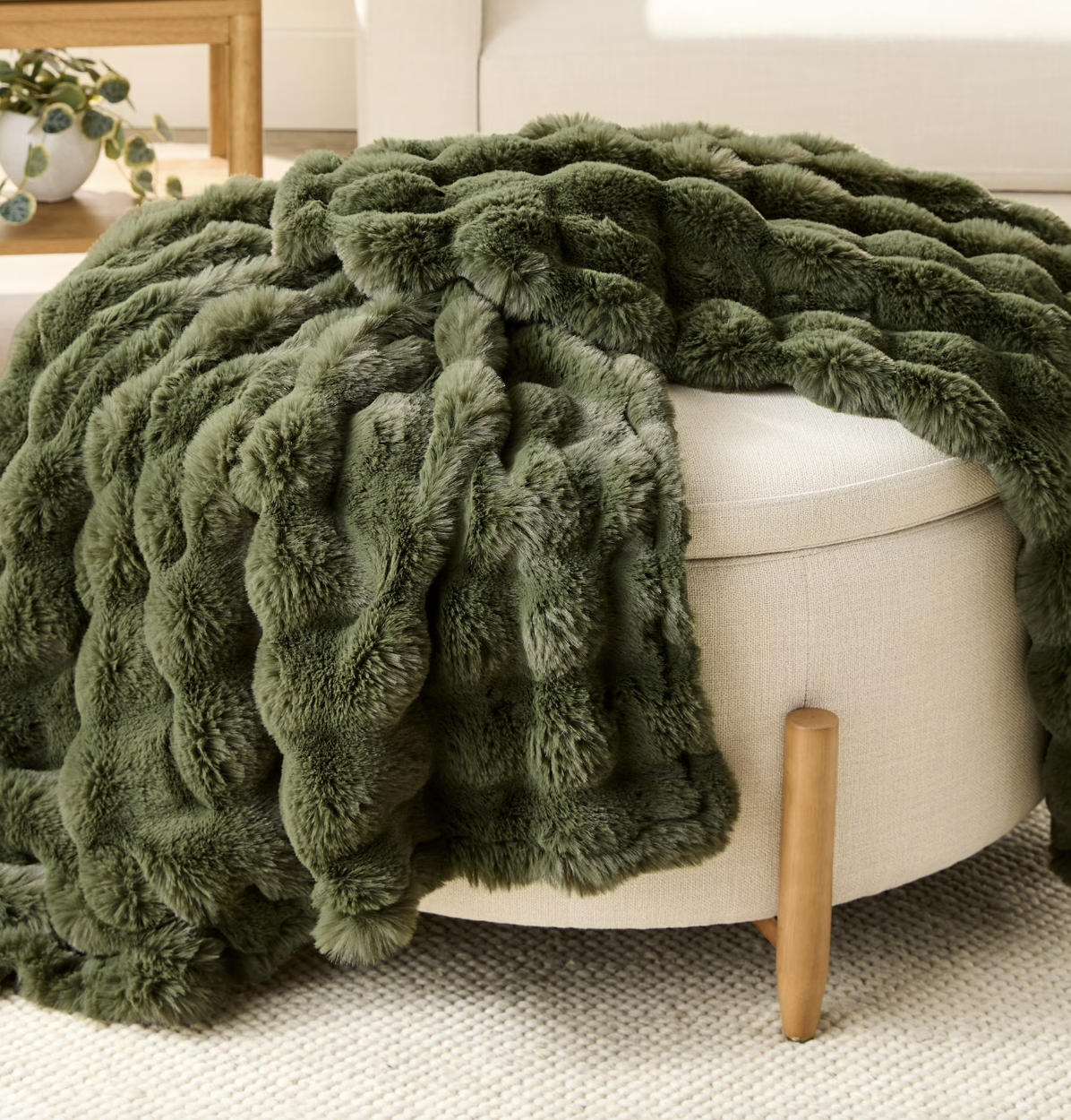 green throw blanket on an ottoman 