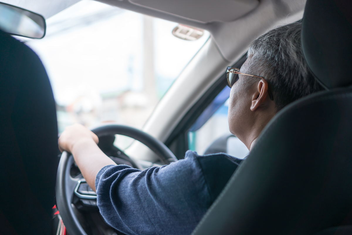 Woman driving car with sunglasses in black car on highway.
