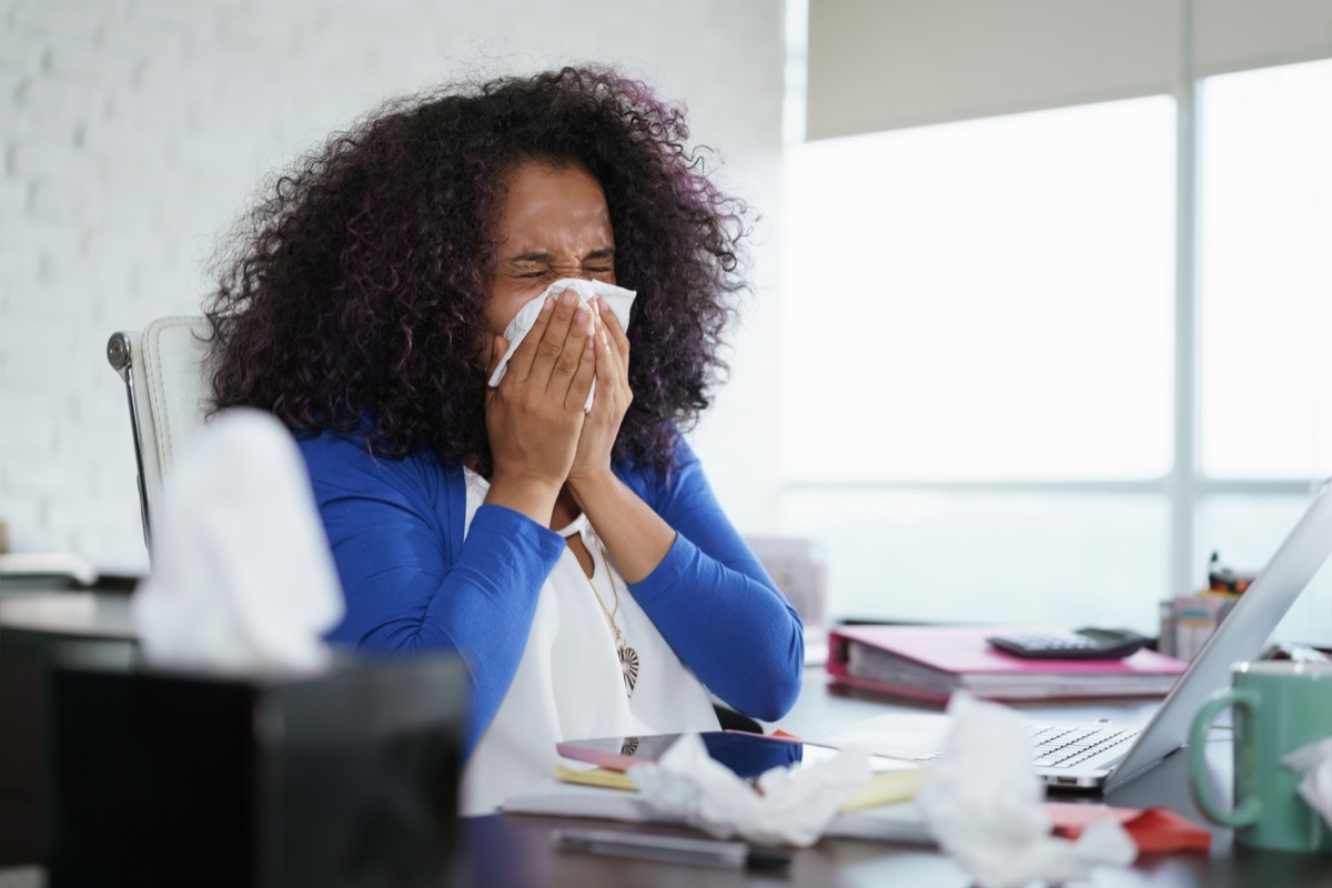 woman sneezing into tissue, signs your cold is serious