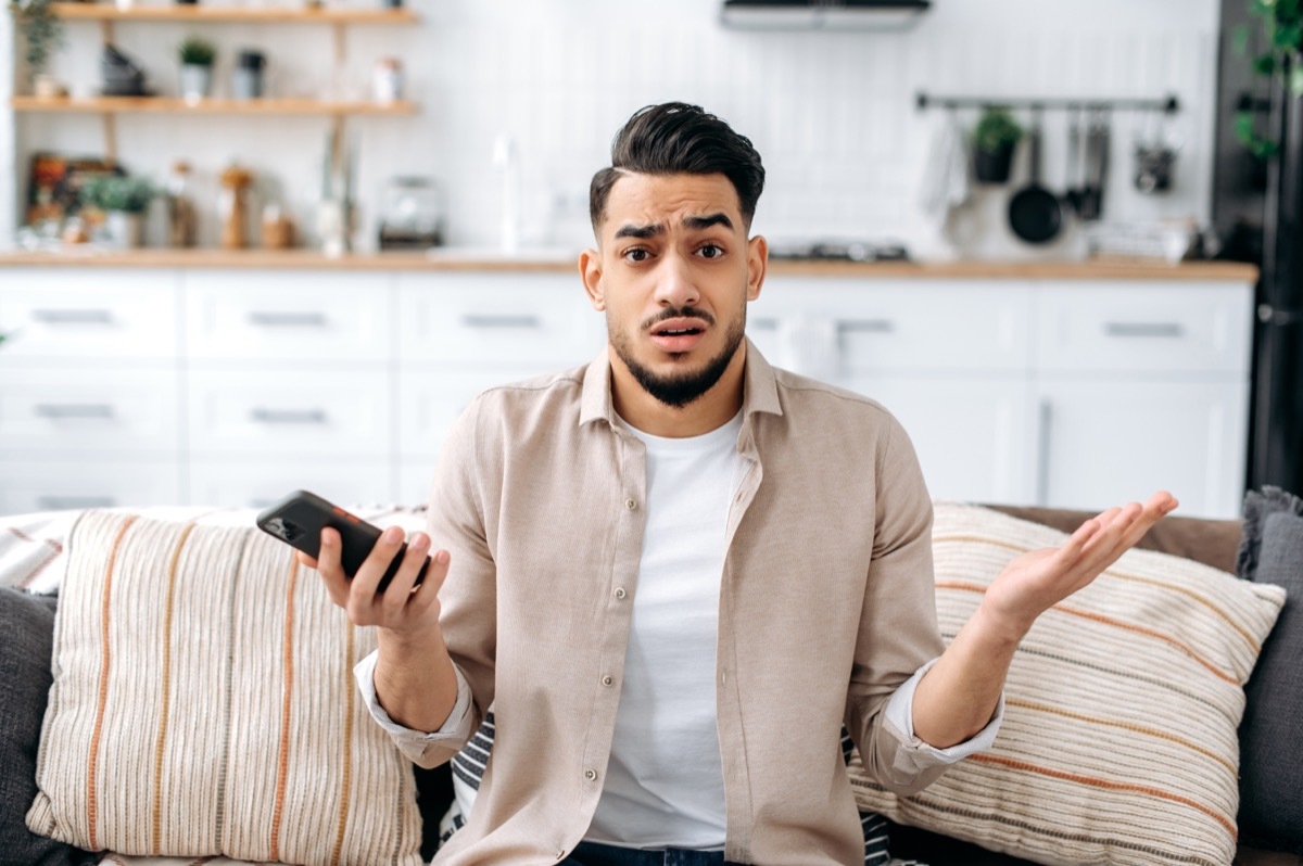 man looking confused while sitting on the couch