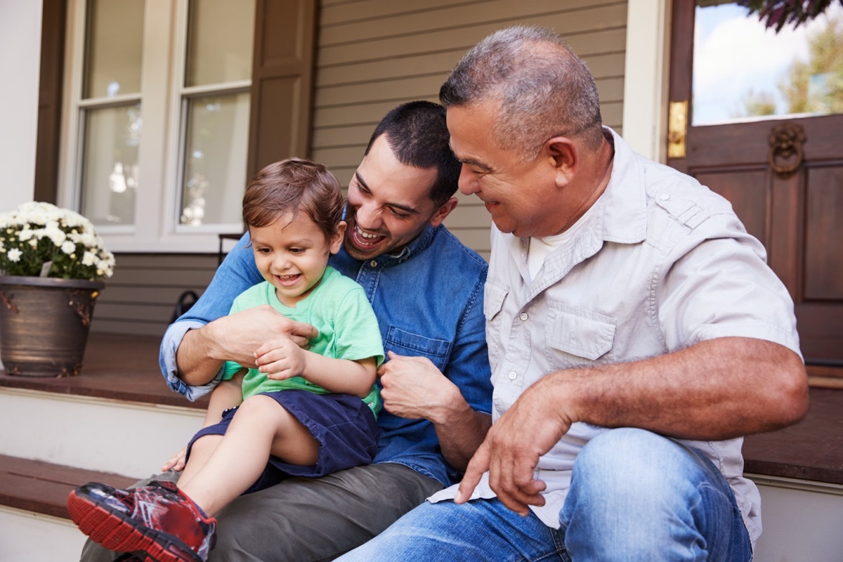 Dad tickling son sitting next to grandfather