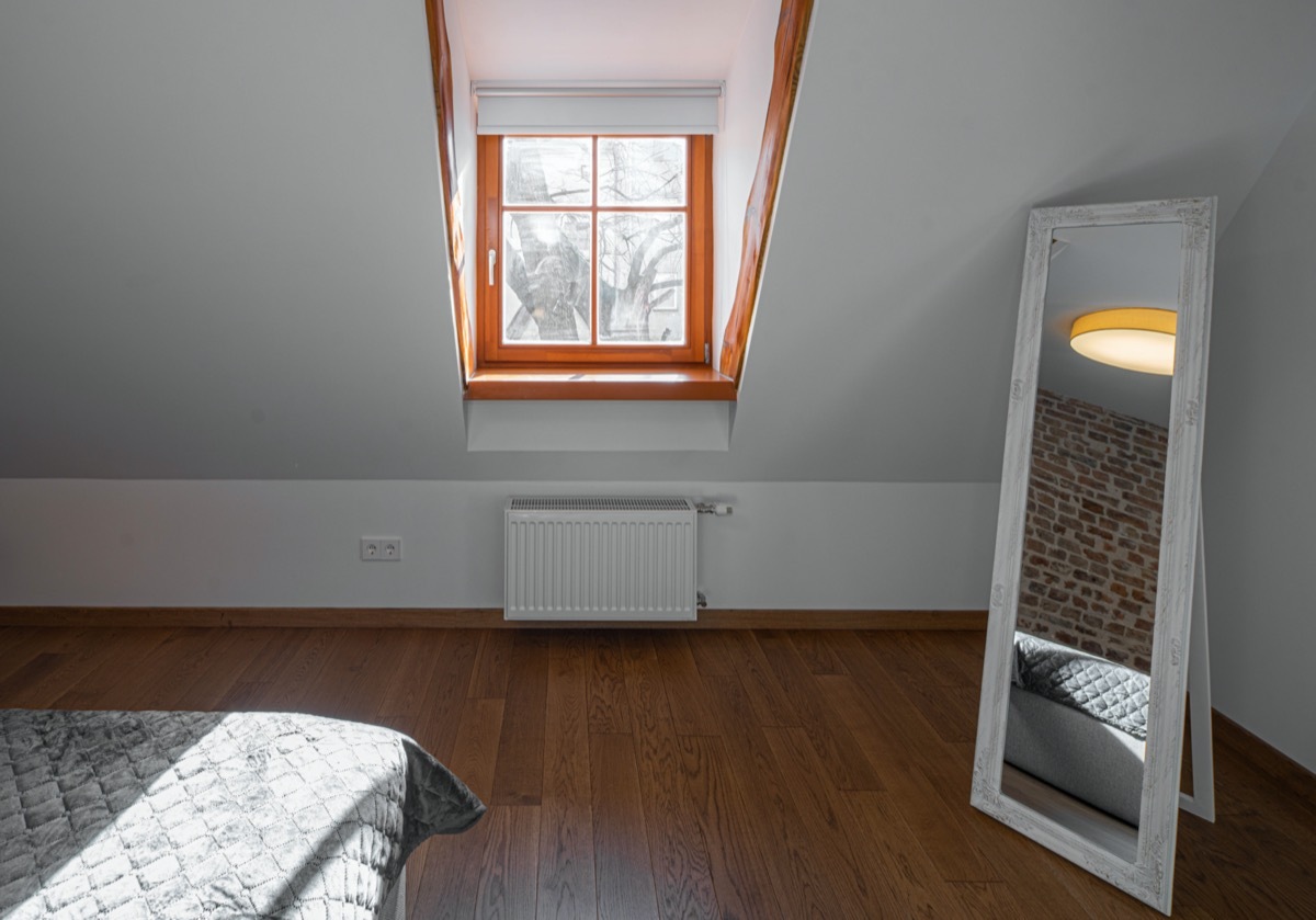 bedroom with mirror, window, and sloped hardwood floor