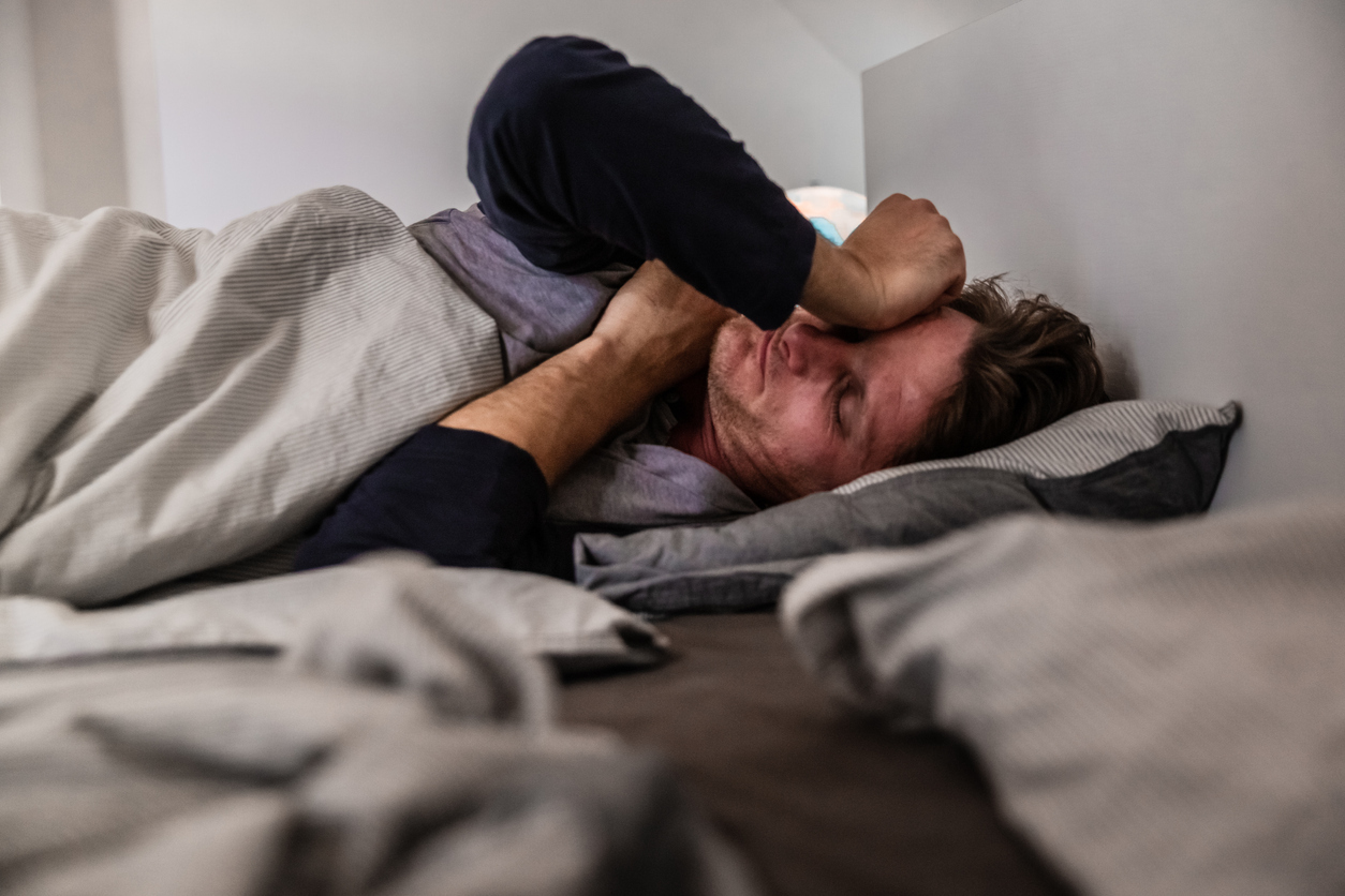 A man lying in bed feeling sick.