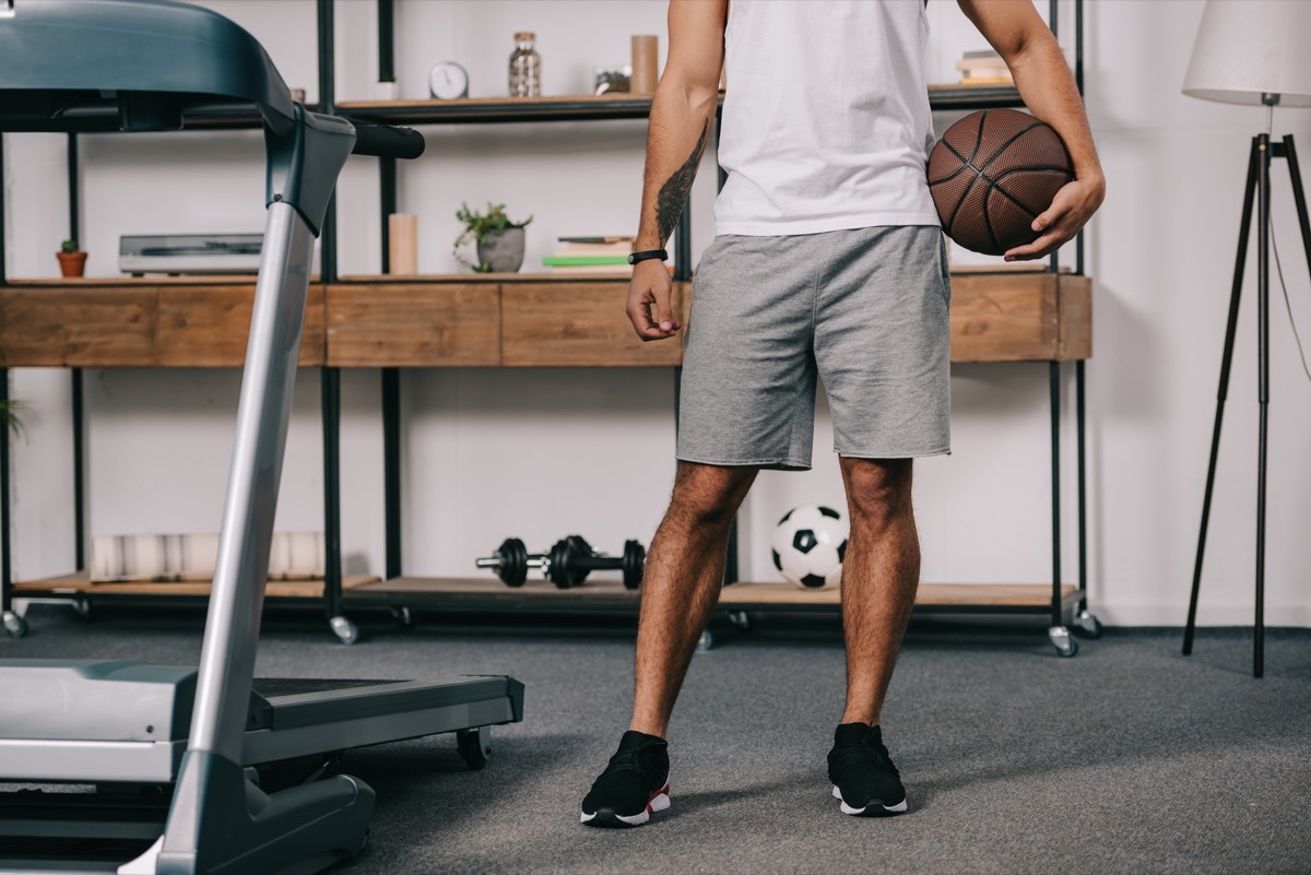 man holding a basketball standing next to a treadmill