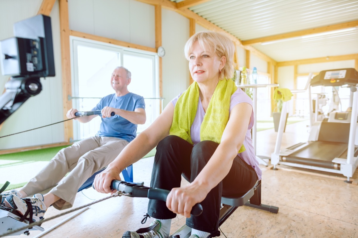 Senior couple in the gym on a rowing machine exercising for better fitness