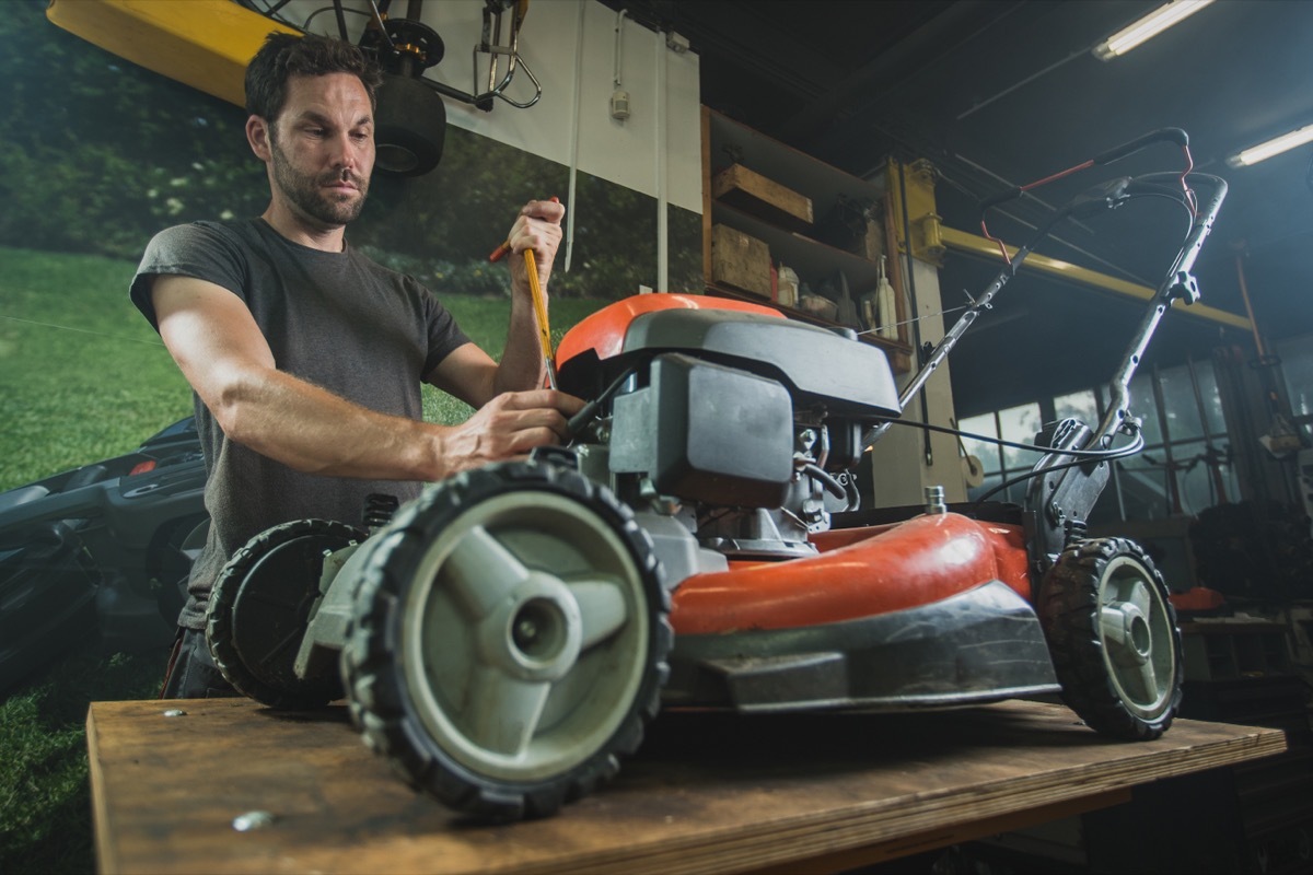 man fixing lawn mower in garage