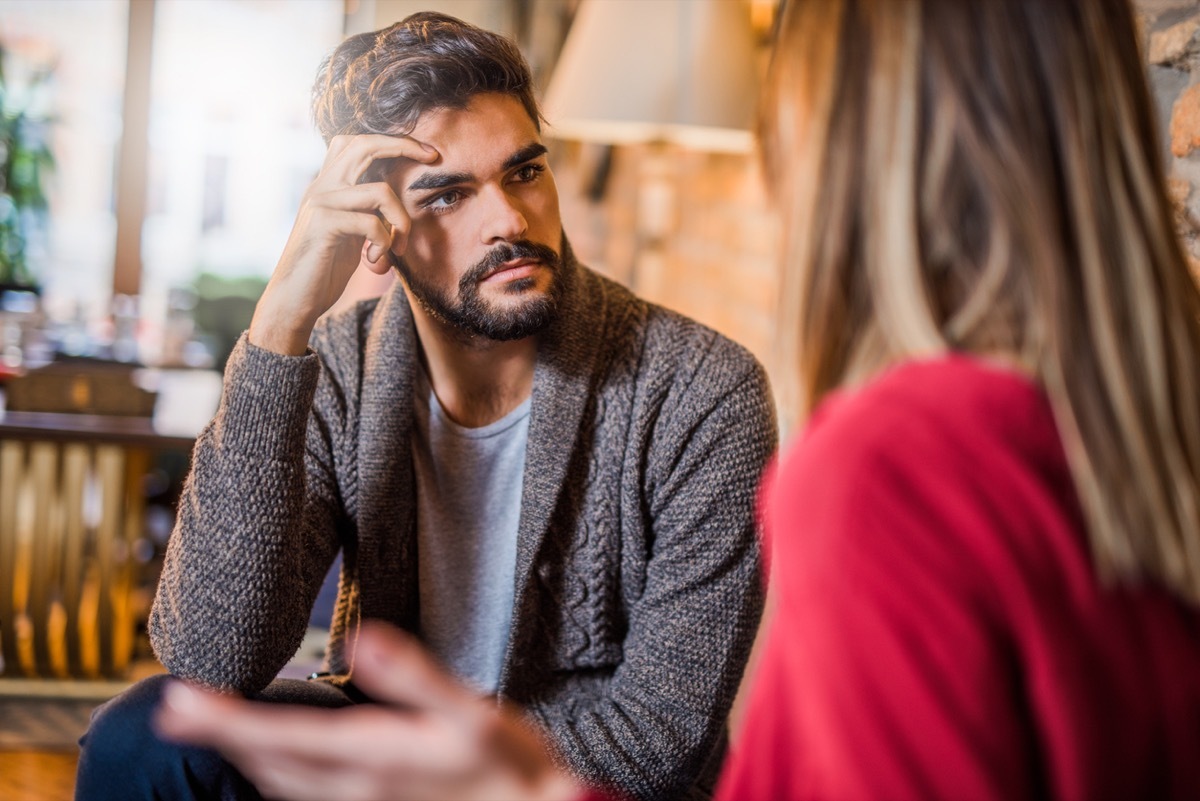 man looking annoyed while listening to a woman speak