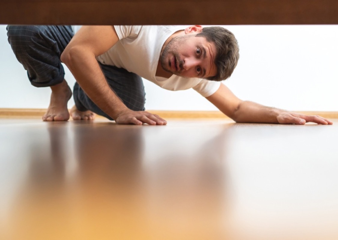 middle aged white man looks under bed