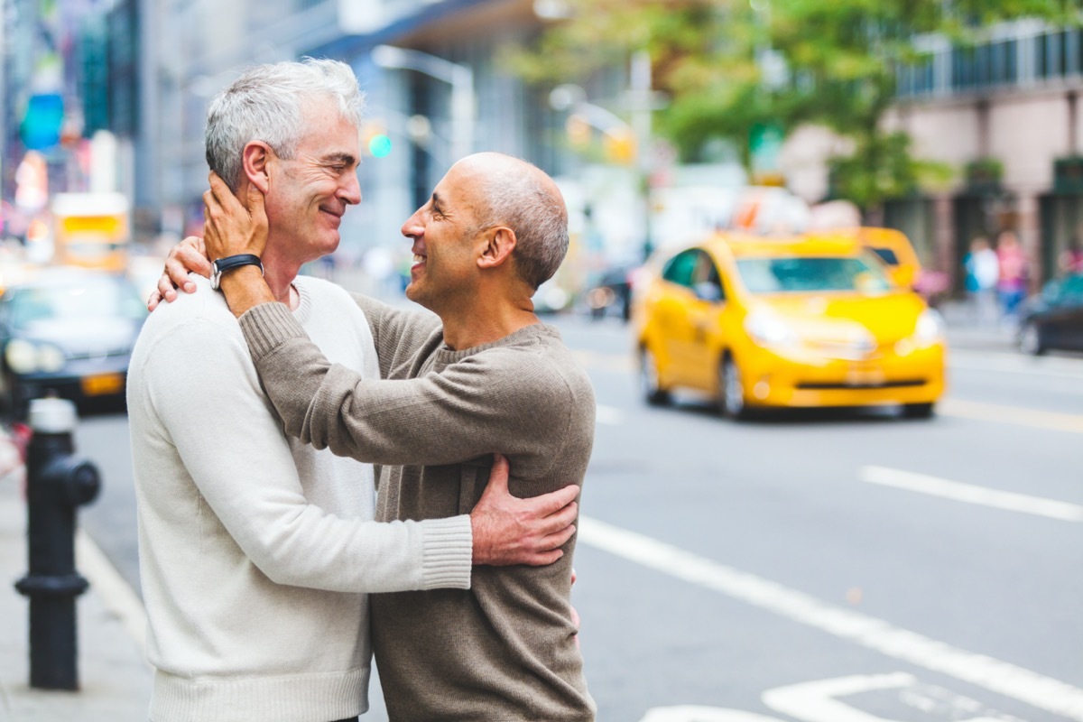 Two senior men hugging on city street