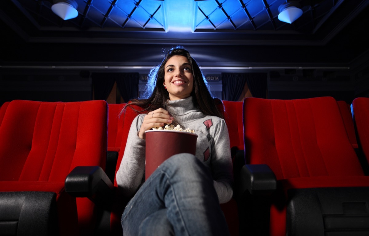 woman watching movie in movie theater alone self-care tips