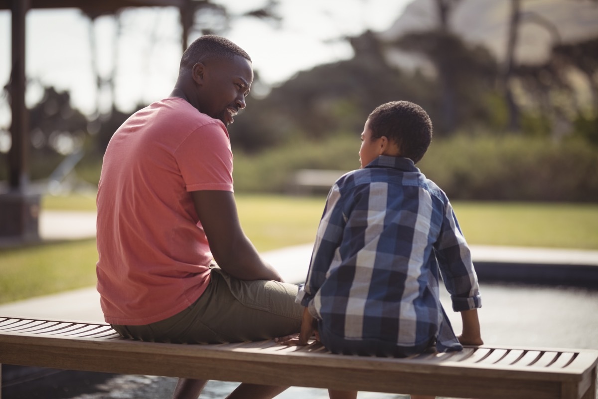 a father sitting down next to his son child and talking