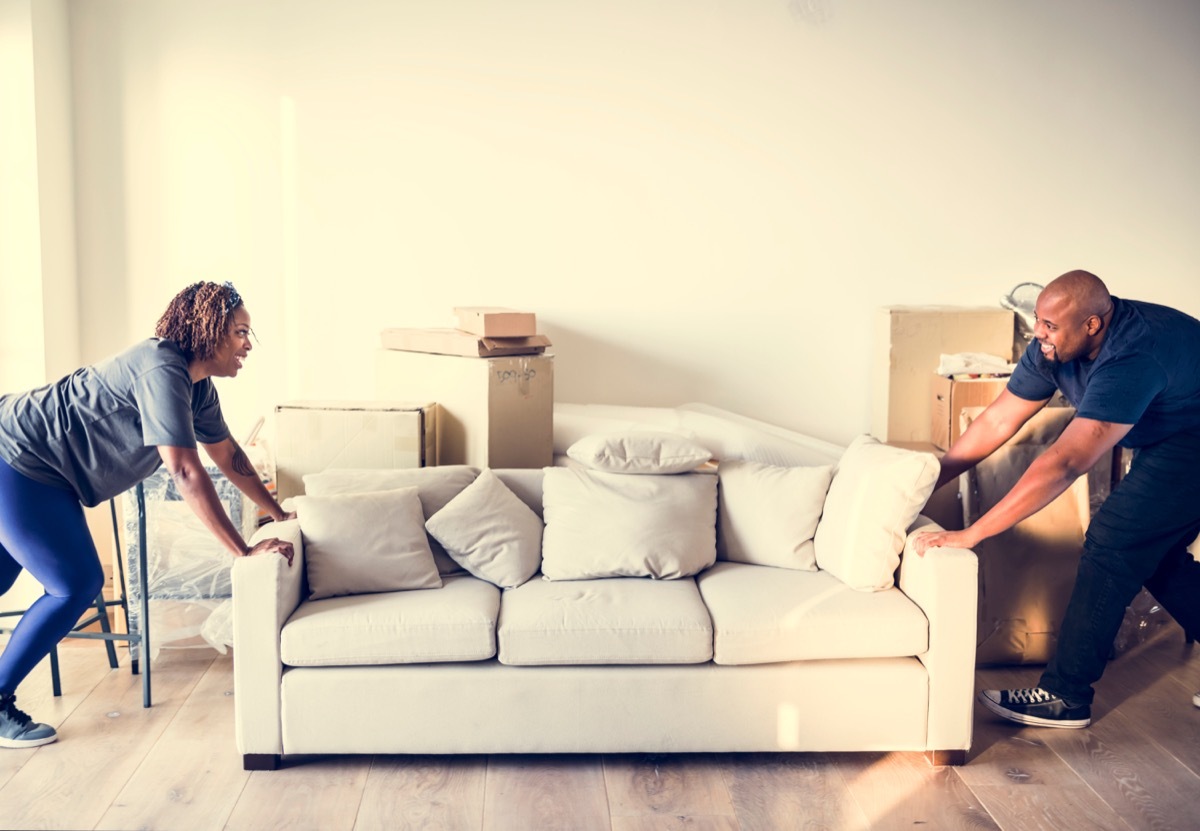couple rearranging their living room by moving their couch around