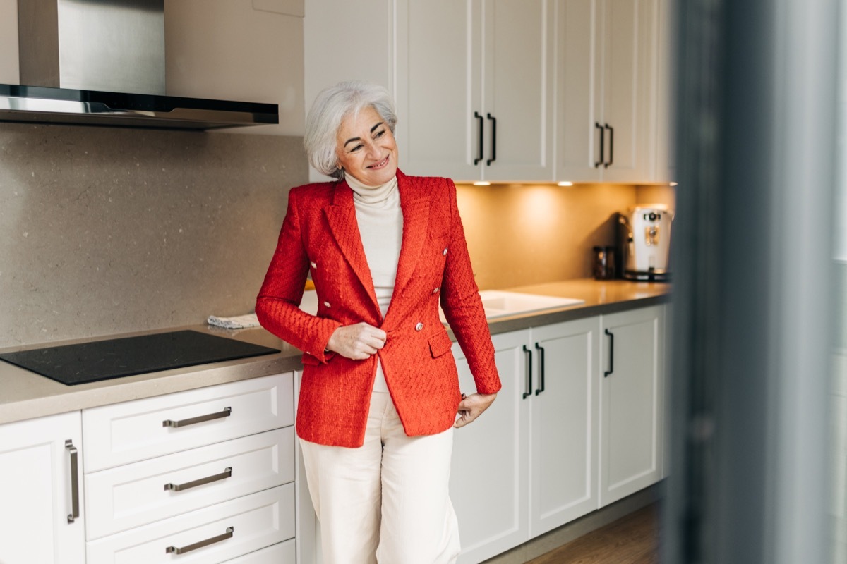 Stylish, happy senior woman trying on red blazer