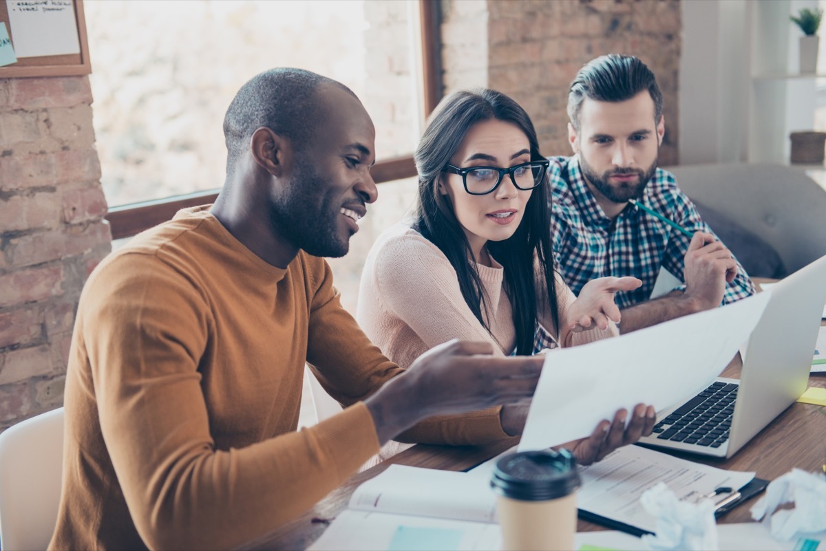 three coworkers in an office working and discussing a project, working mom