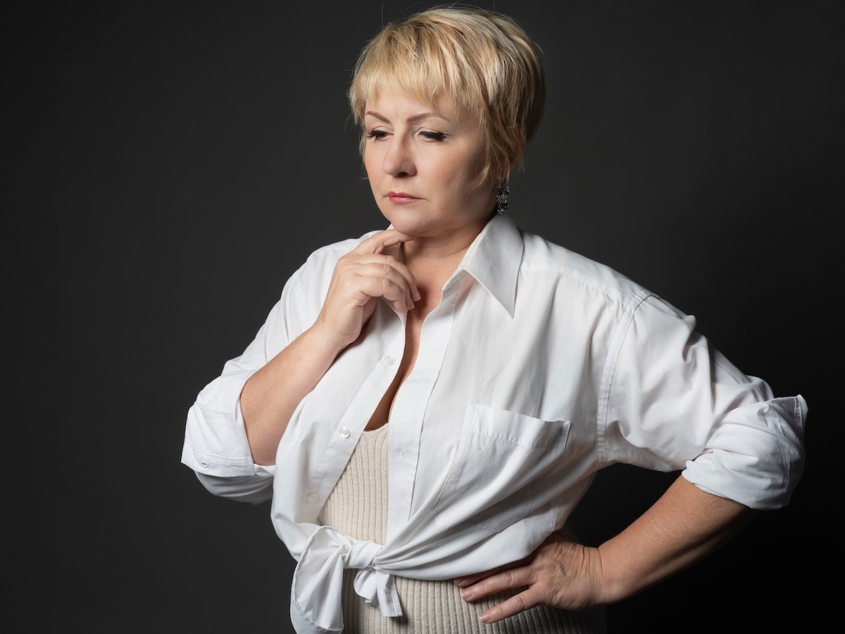 Portrait of a thoughtful adult woman with short blonde hair in a stylish white shirt .