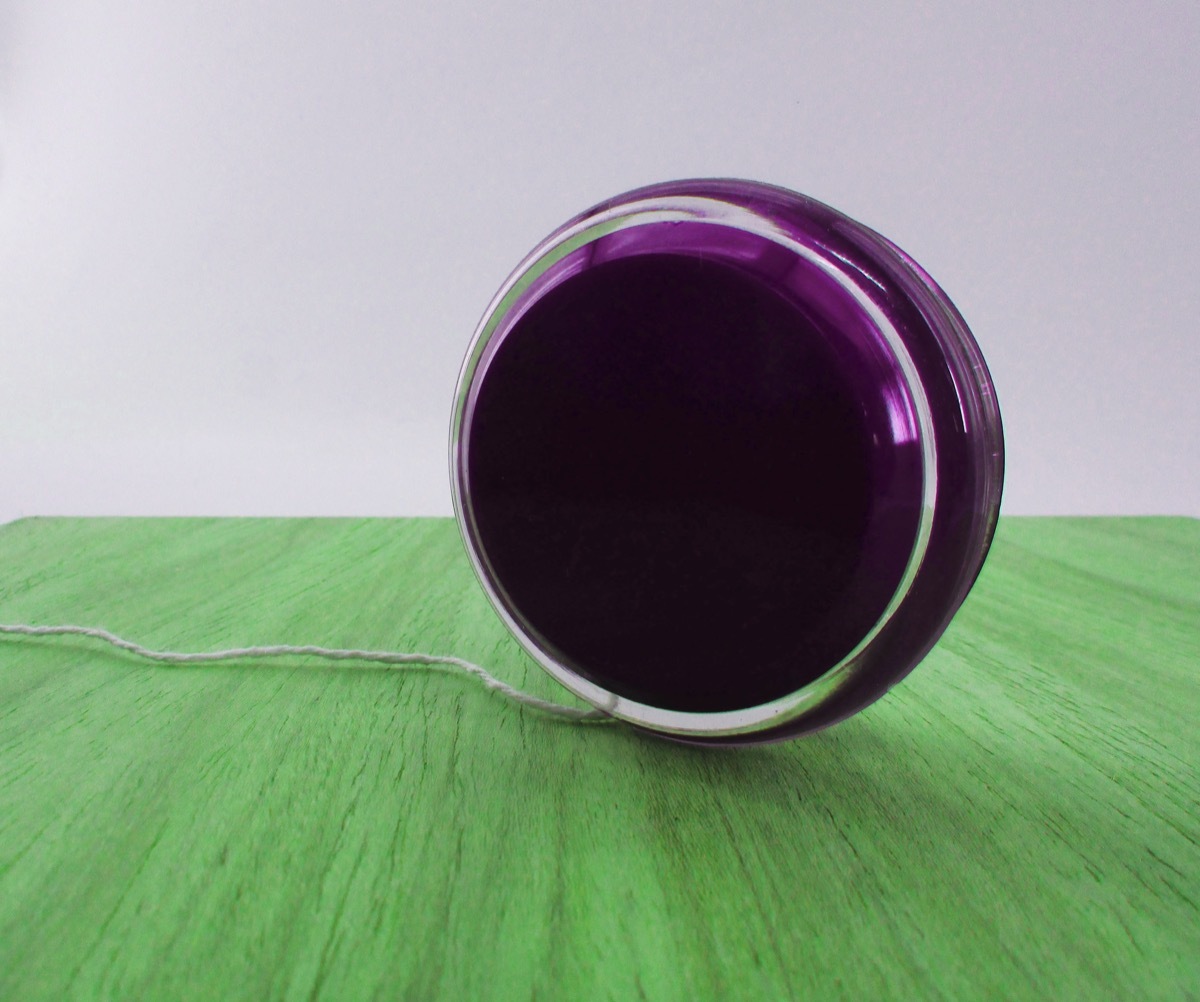 a purple yo yo rests on a green table