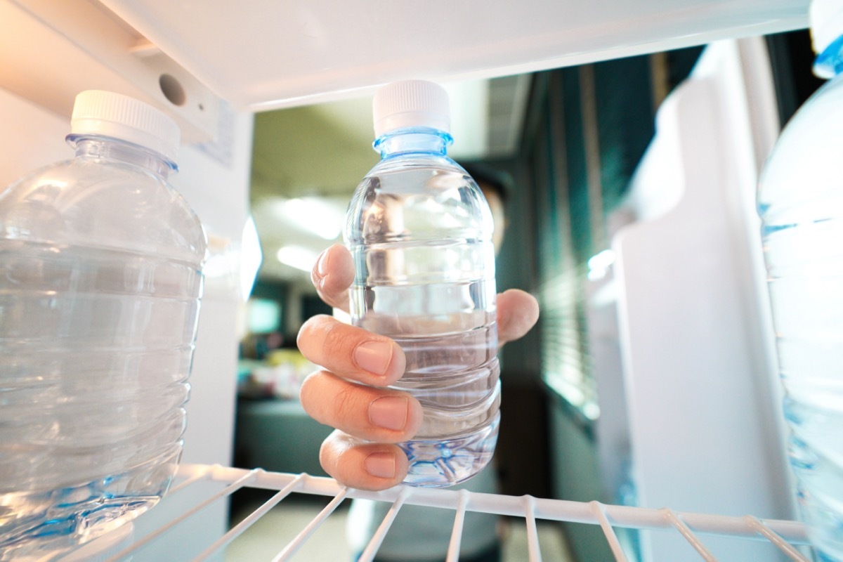 Person grabbing a water bottle from their fridge.