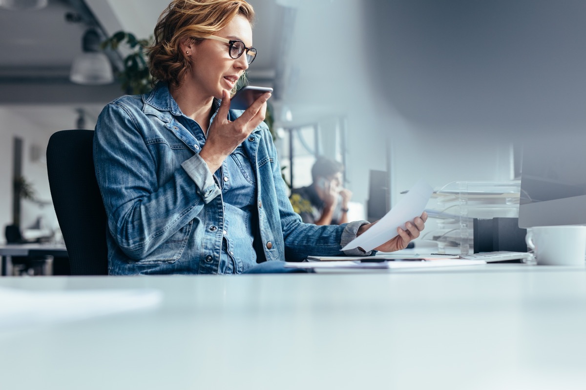 Woman sitting in office using speech-to-text on phone
