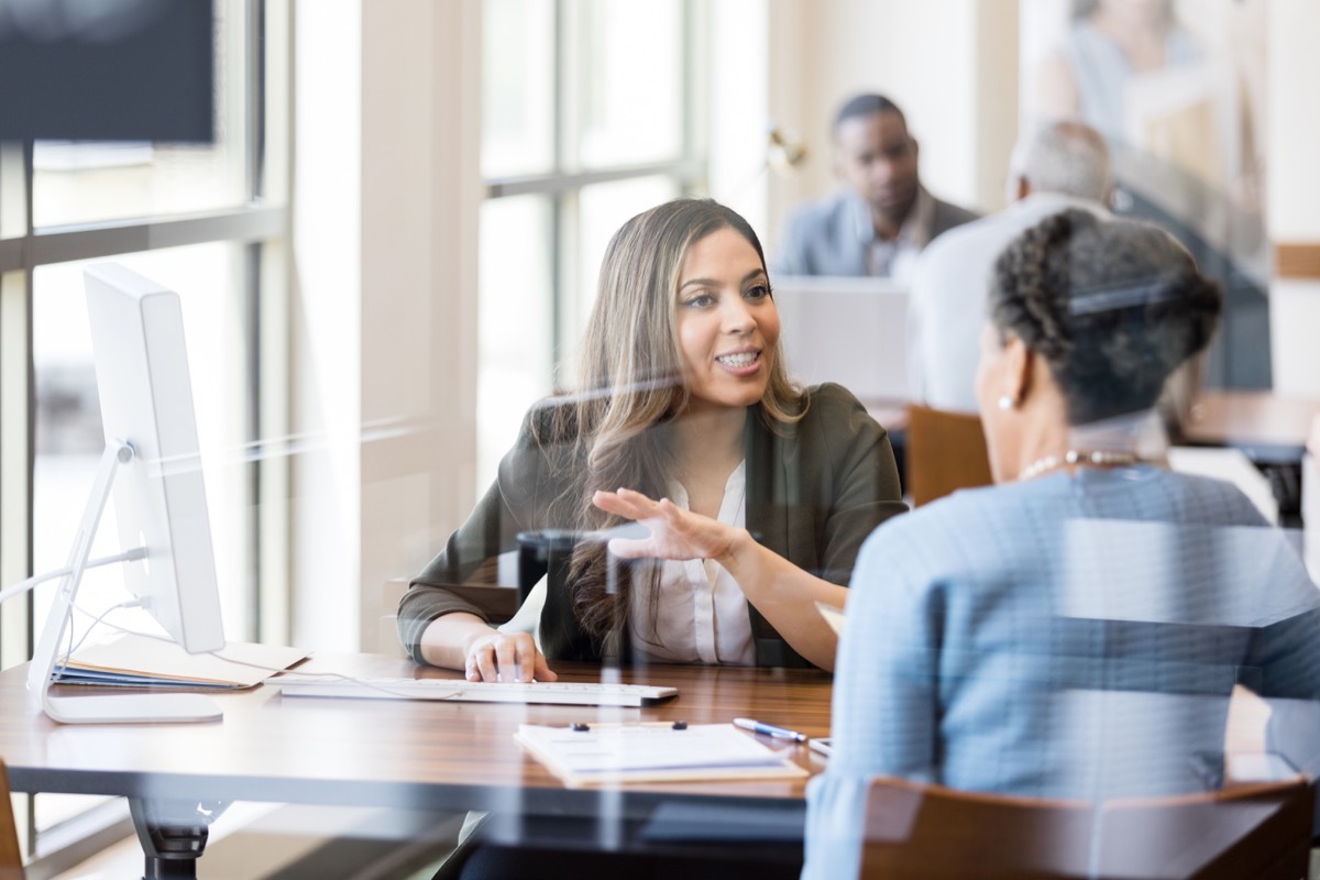 A female bank employee gestures as she explains banking services to a female customer