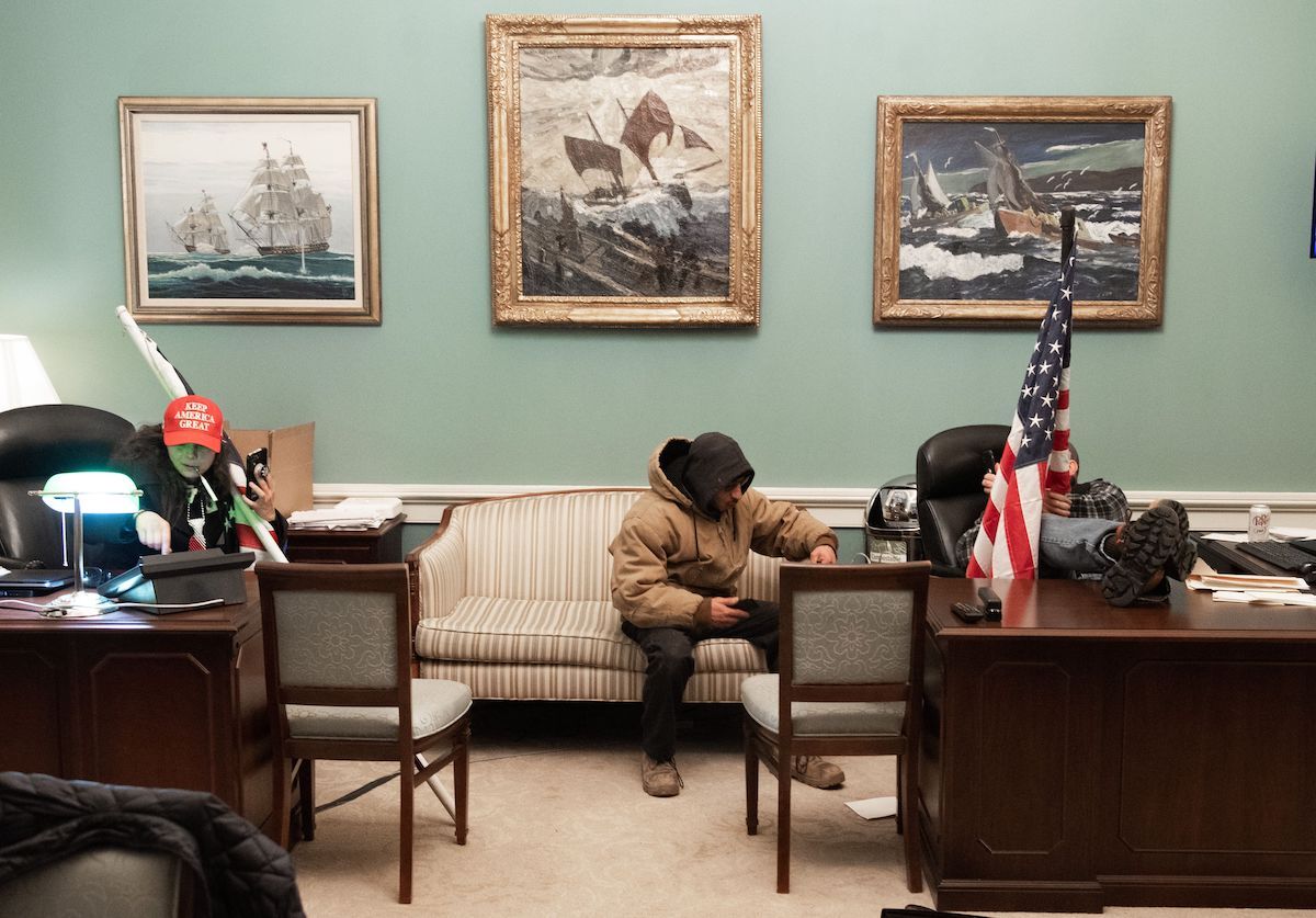 Supporters of US President Donald Trump sit inside the office of US Speaker of the House Nancy Pelosi as he protest inside the US Capitol in Washington, DC, January 6, 2021. - Demonstrators breeched security and entered the Capitol as Congress debated the a 2020 presidential election Electoral Vote Certification.