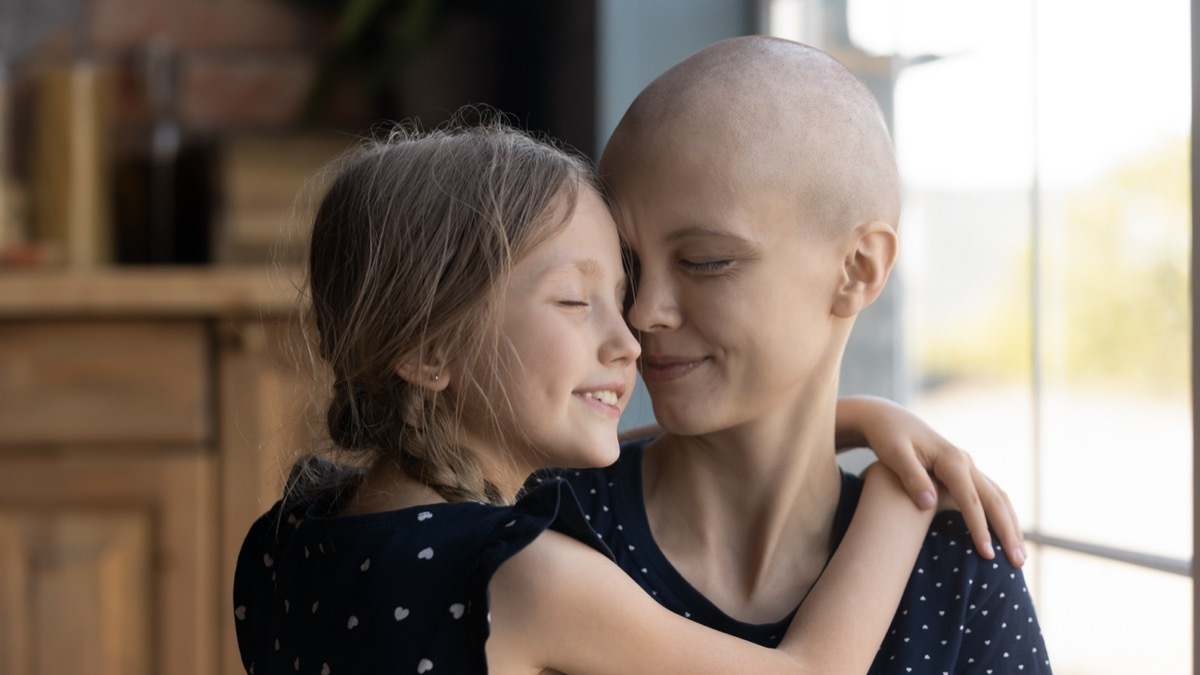 Happy young cancer patient sick mother and little daughter hug